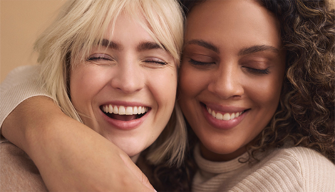 Two women hugging and laughing.