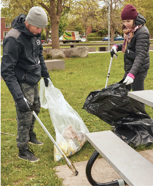 Two people picking up trash in a park.